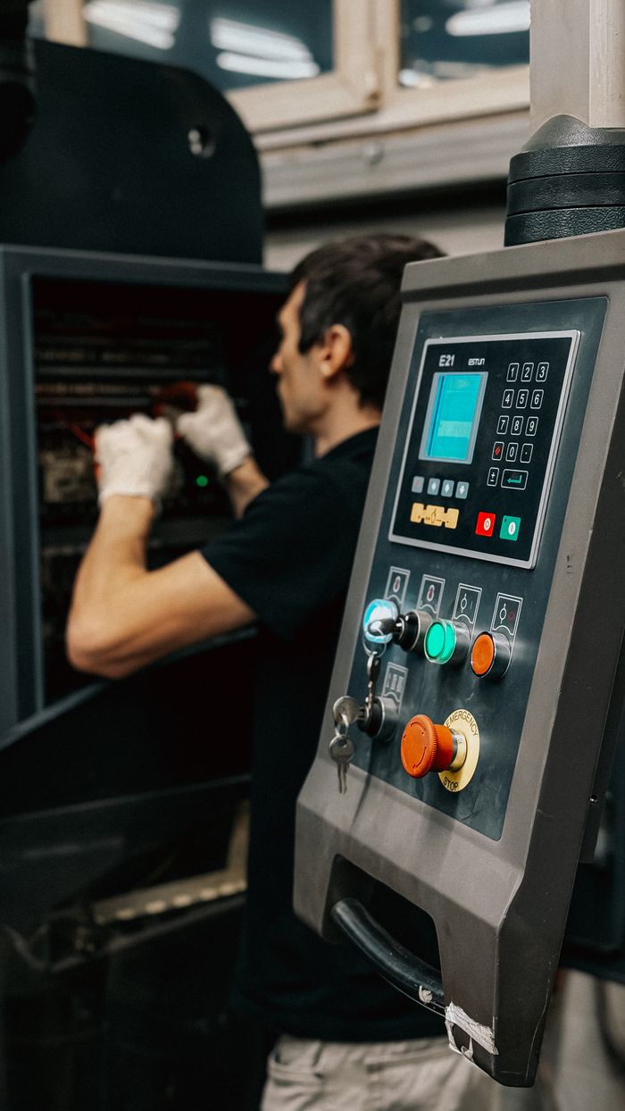 Technician using a control panel to manage machinery operations in a factory.